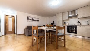 A modern kitchen with a dining table, chairs, and a bowl of fruit. - Casa Erika, relax in Tuscany   (Partino)