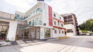 A hotel with a modern design, featuring a prominent red accent on the facade, multiple balconies, and a gated entrance. - Hotel Quinta Santa Anita (Playa del Carmen)