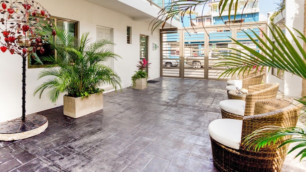A spacious indoor area with a tiled floor, wicker furniture, and potted plants. - Hotel Quinta Santa Anita (Playa del Carmen)