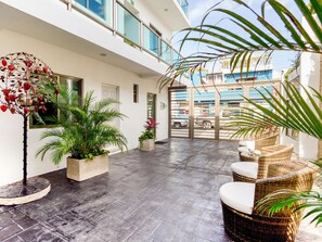 Un espacio interior amplio con suelo de baldosas, muebles de mimbre y plantas en macetas.