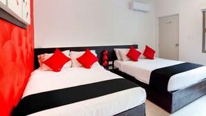 A hotel room with two beds, each with white bedding and red pillows, a black headboard, and a wall-mounted air conditioner. - Hotel Quinta Santa Anita (Playa del Carmen)
