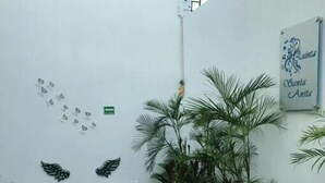 A courtyard with a white bench, palm trees, and a wall with decorative elements. - Hotel Quinta Santa Anita (Playa del Carmen)