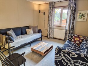 A furnished living room with a sofa, a coffee table, a chair, and a radiator. - Amsterdam Farm Lodge: Family apartment (Amsterdam)