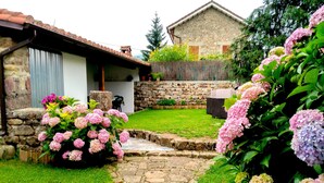 A stone house with a tiled roof, a stone wall, and a grassy yard with a stone pathway. - House of integral rent in the center of Cantabria. 8 people (La Serna de Iguña)