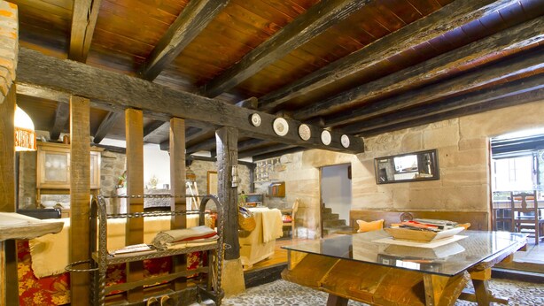 A rustic kitchen with exposed wooden beams, stone walls, and a stone floor. - House of integral rent in the center of Cantabria. 8 people (La Serna de Iguña)