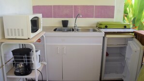 Een kleine keuken met een magnetron, spoelbak en een kleine koelkast.