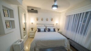 Een slaapkamer met een bed, nachtkastjes, een verwarming en een raam met gordijnen.