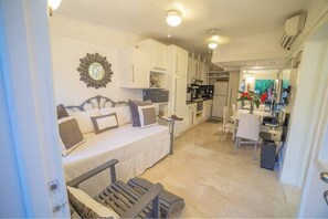 Une chambre d’hôtel de taille réduite, équipée d’un lit, d’un bureau et d’une kitchenette.