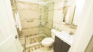 Een moderne badkamer met een douchecabine van glas, een toilet, een wastafel en een spiegel.