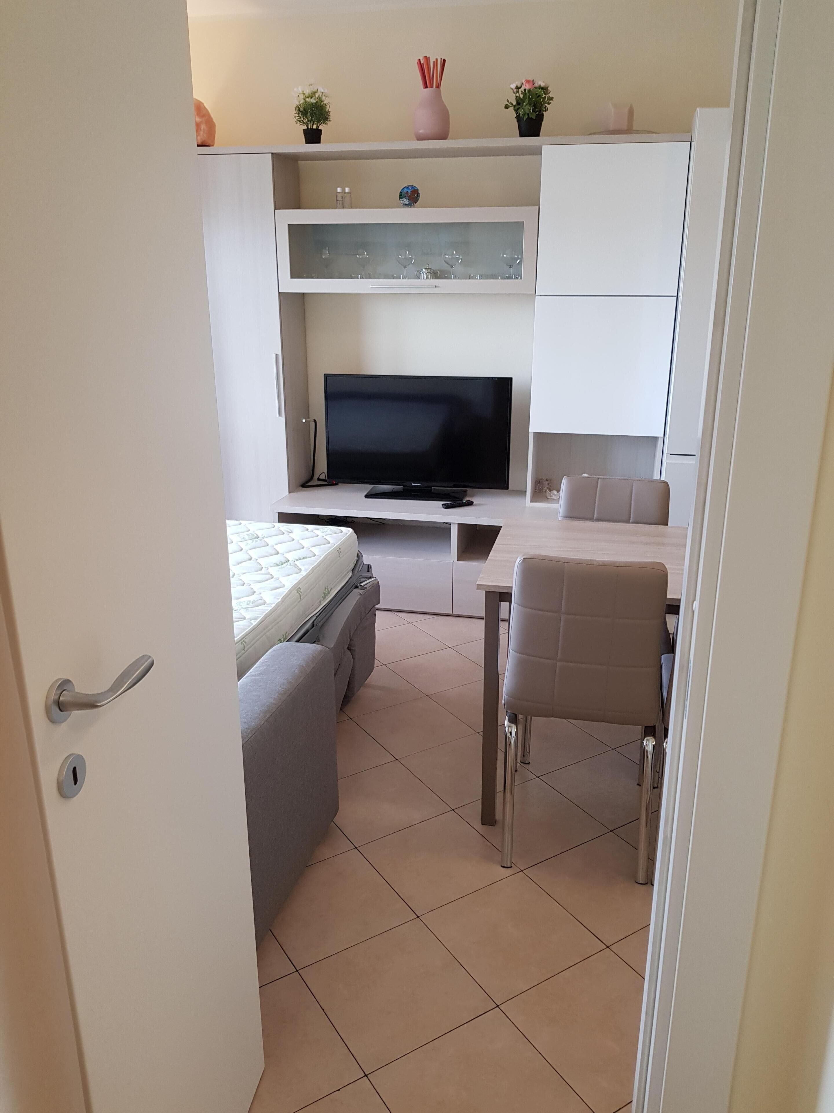 A modern, compact living space with a television, sofa, and dining area.