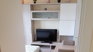 Un espace de vie moderne et compact, comprenant un téléviseur, un canapé et un coin repas.