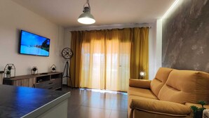 A modern kitchen with a built-in oven, a dining area with a yellow sofa, and a large window with curtains. - Apartment with large terrace and beautiful pool view, solarium, private parking (Costa Adeje)