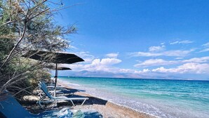 A beach with lounge chairs, umbrellas, and a pebble beach.