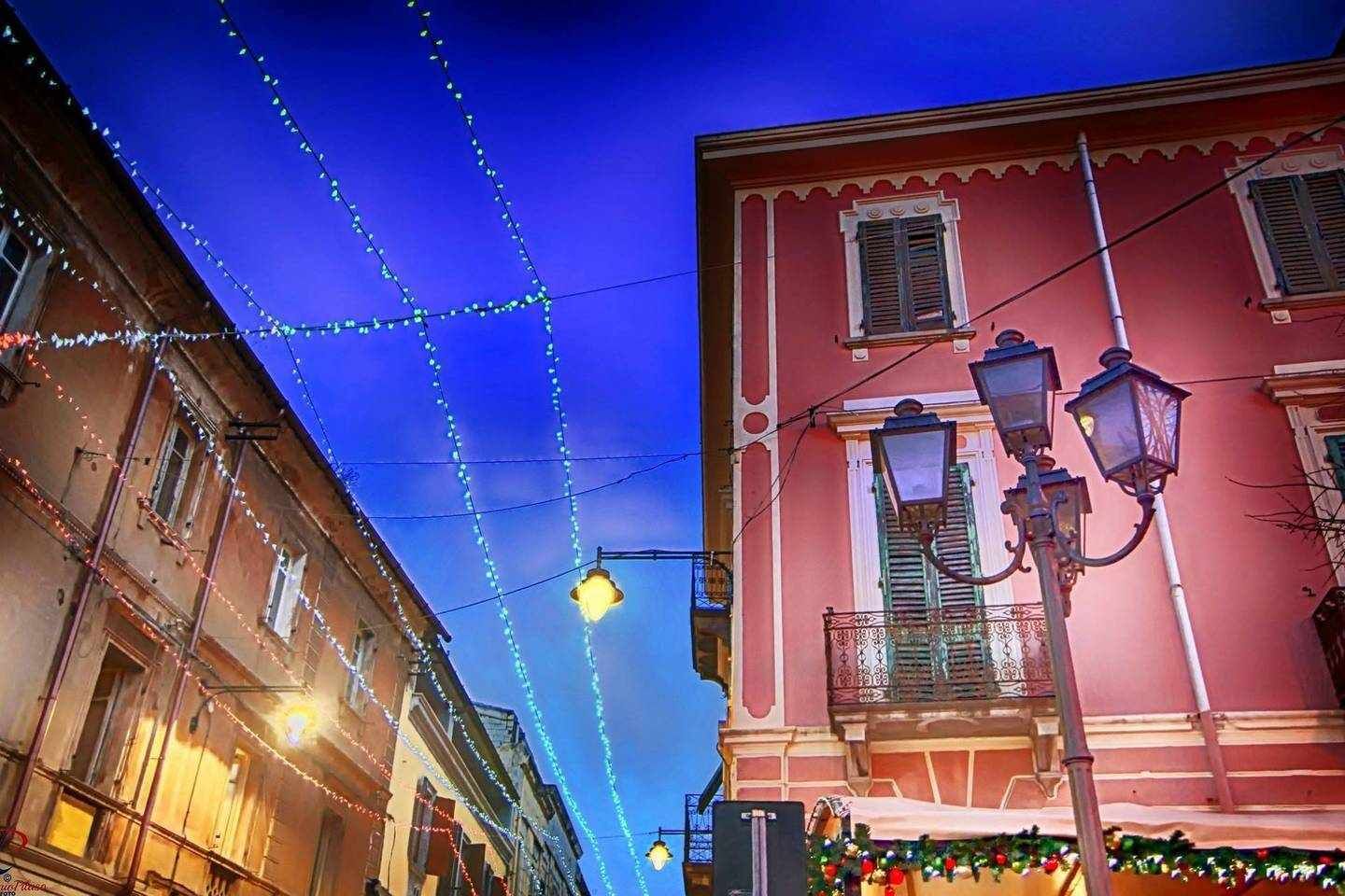 A street with buildings, string lights, and a street lamp.