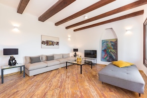A living room with a sofa, ottoman, coffee table, TV, and artwork. - Exclusive holiday home in Sveta Marina, Istria, Croatia - right by the sea (Sveta Marina)