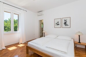 A bedroom with a wooden bed, white curtains, and two framed pictures on the wall. - Exclusive holiday home in Sveta Marina, Istria, Croatia - right by the sea (Sveta Marina)