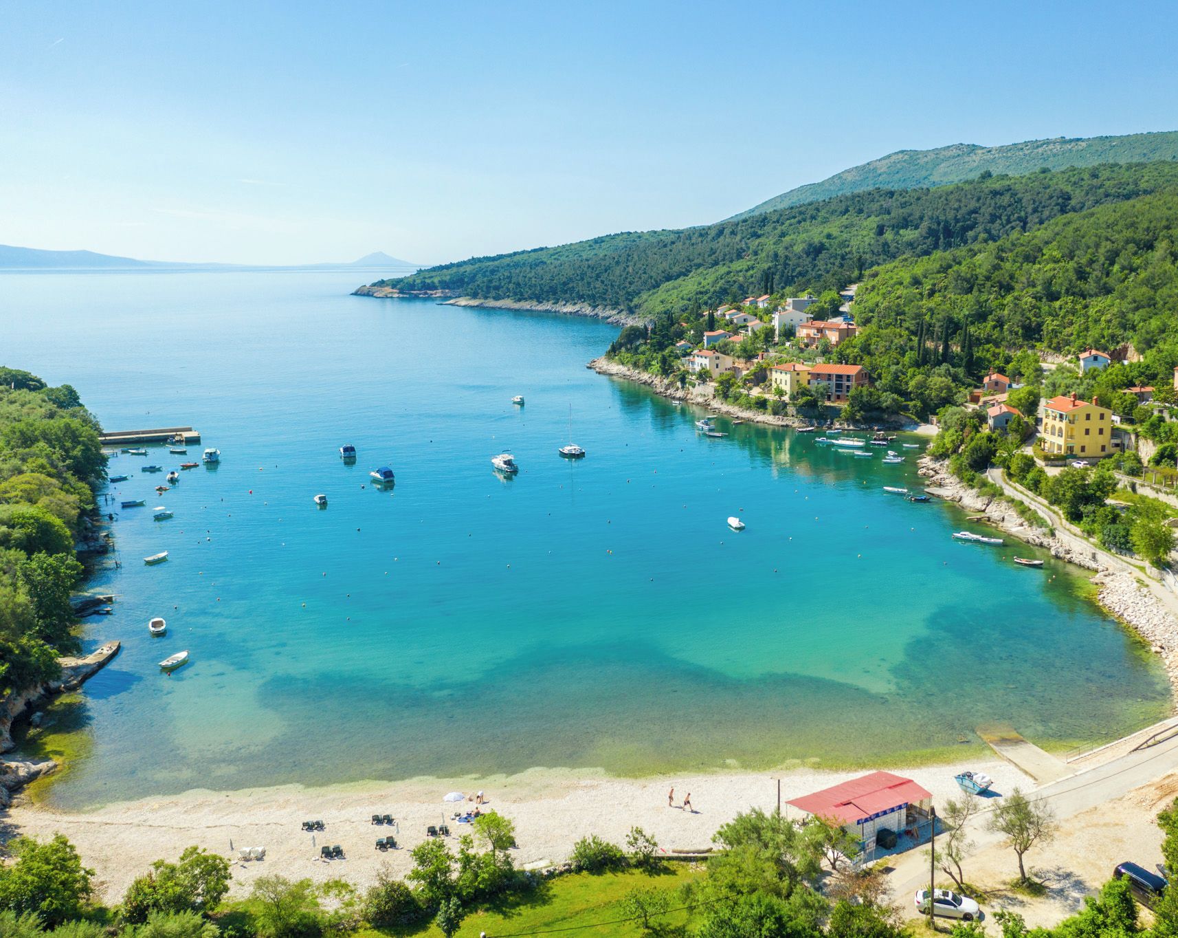 A coastal town with a clear view of the sea, boats, and buildings along the shore.