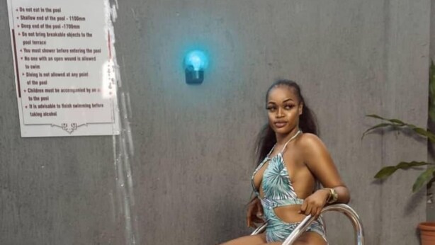 A person sitting on a poolside chair by a pool with a sign listing poolside rules. - SS3 Boutique Hotel (Port Harcourt)