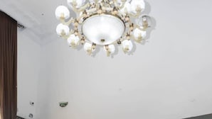 A living room with a large chandelier, a flat-screen TV, and blue sofas. - SS3 Boutique Hotel (Port Harcourt)