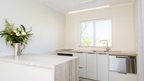 Une cuisine moderne avec des meubles blancs, un lave-vaisselle en acier inoxydable et un plan de travail en marbre.