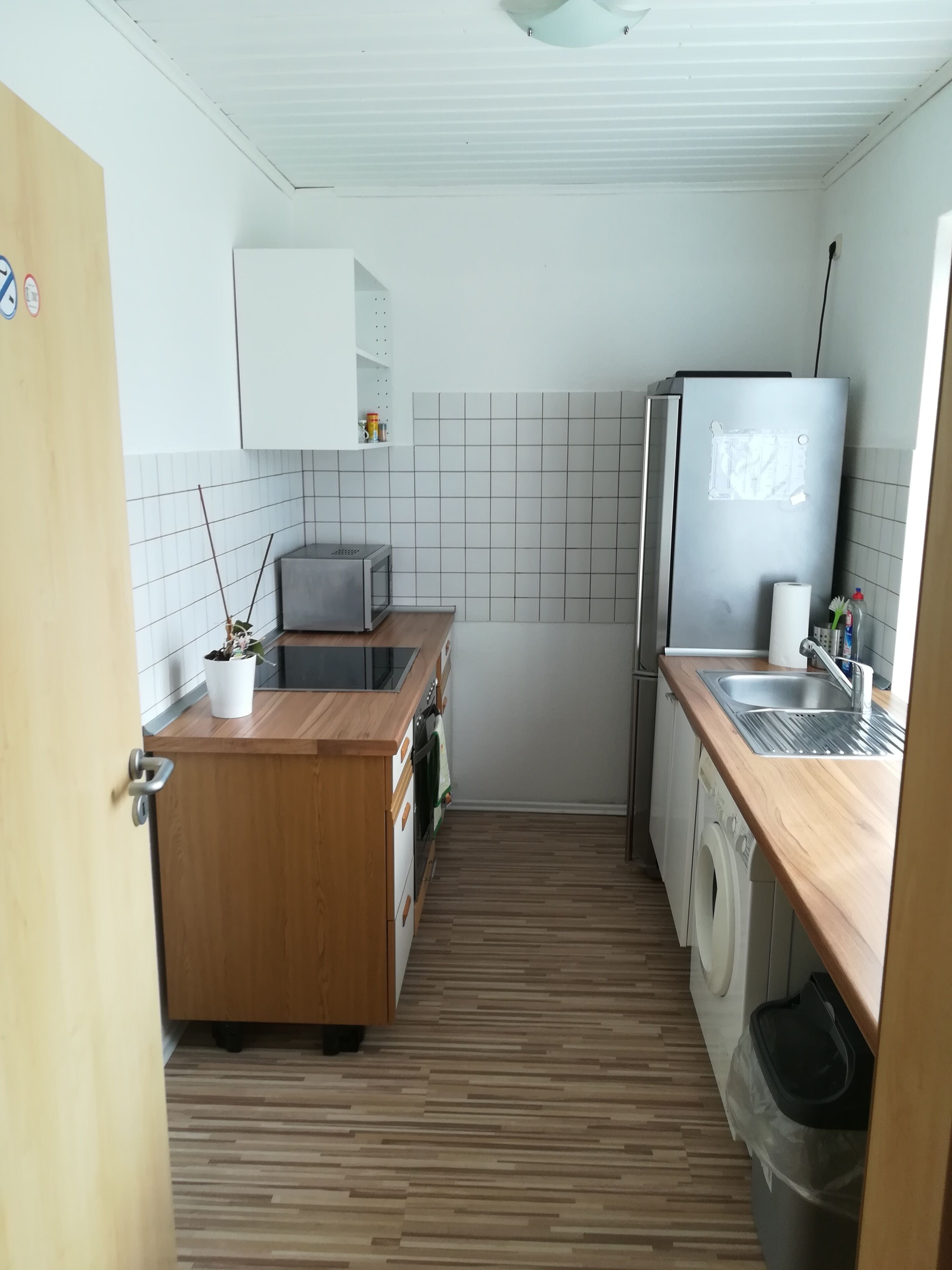A compact kitchen with a microwave, refrigerator, sink, and wooden countertop.