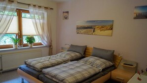 Un dormitorio con una cama doble, una mesita de noche, una ventana con cortinas y un cuadro colgado en la pared.