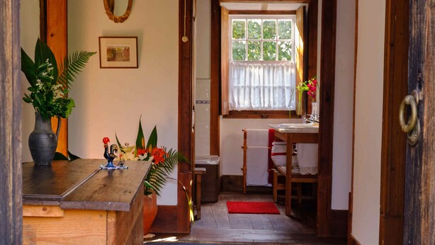 Een houten interieur met een receptiebalie, een welkomstmat en een uitzicht op een eetgedeelte.
