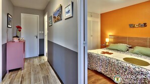 A hotel room with a bed, a nightstand, and a wall-mounted sign. - Cottage of Suzette ---- (LA FORET-FOUESNANT)