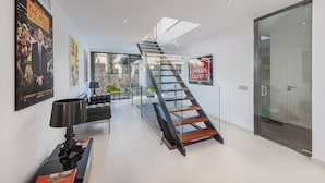 A modern interior with a glass staircase, a sofa, and a lamp.