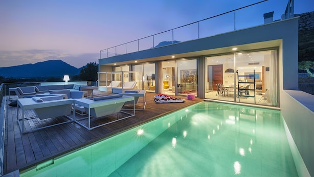 A modern house with a swimming pool, outdoor seating, and a view of mountains.