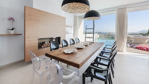 A modern dining area with a wooden table, black chairs, and pendant lights.