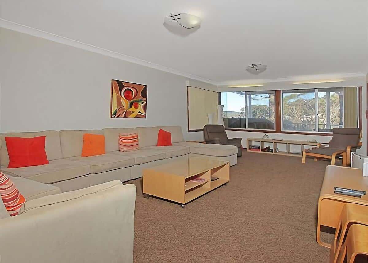 A modern living room with a sectional sofa, a coffee table, and a dining area with a table and chairs.