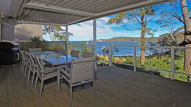 Une terrasse extérieure avec une table et des chaises, offrant une vue panoramique sur la côte.