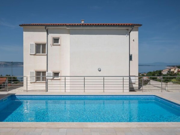 Un bâtiment à deux étages avec une piscine devant.