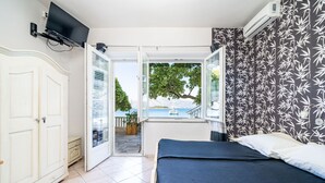 Ein Schlafzimmer mit Bett, Fernseher, Kleiderschrank und Meerblick.