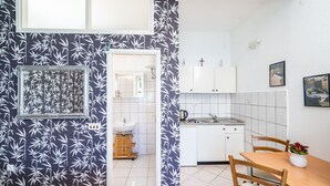 Eine kleine Küche mit weißen Schränken, einem Spülbecken und einem Essbereich mit Tisch und Stühlen.