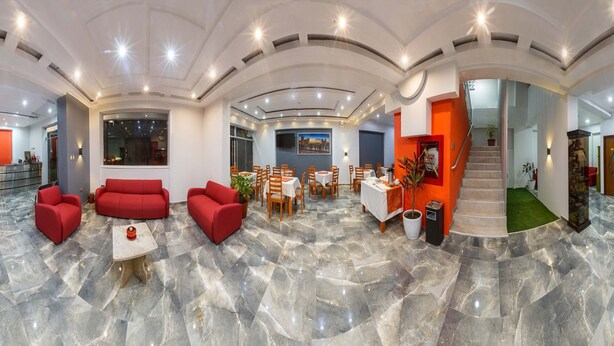 Eine großzügige Lobby mit Marmorboden, roten Sofas und einem Essbereich mit Holztischen und -stühlen.
