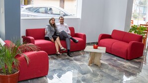 Eine moderne Lobby mit roten Sofas, einem Holztisch und einer Topfpflanze.