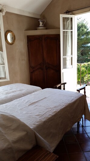 Una habitación con dos camas, un armario de madera, un espejo y una ventana con cortinas.