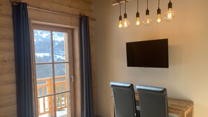 A room with a wooden ceiling, a large window with curtains, a desk with two chairs, and a mounted TV. - The mountain with family or friends ... the cottage "Huski" is for you! (Valloire)