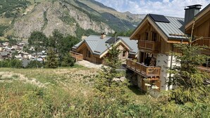A mountain lodge with wooden cabins, a stone foundation, and a view of a valley and mountains. - The mountain with family or friends ... the cottage "Huski" is for you! (Valloire)