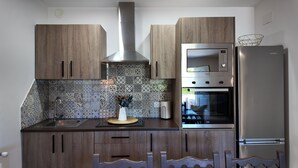 Eine moderne Küche mit Holzschränken, einer Edelstahl-Dunstabzugshaube, einem Backofen und einem Kühlschrank.