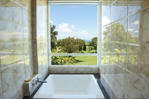 Un ba ño con un ventanal grande, una bañera y paredes de mármol.