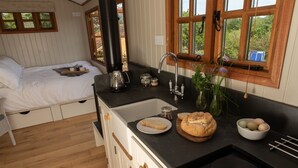 Une petite cuisine équipée d’un évier, d’une cuisinière et d’un lit avec une table à plateau pour le petit-déjeuner.