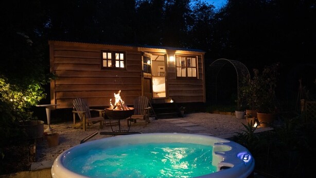 Une cabane en bois avec un bain à remous et un foyer extérieur.