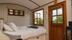 Une chambre à coucher avec un lit, des fenêtres, une porte et une cheminée.