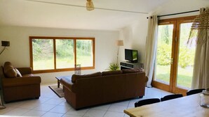 Una sala de estar con sofá, televisor y una mesa de comedor.
