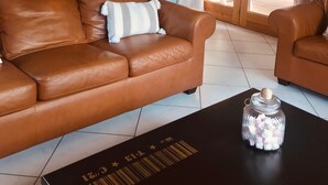 Una sala de estar con un sofá de cuero marrón, un tarro de malvaviscos y una mesa negra con código de barras.