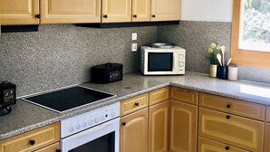 Una cocina con armarios de madera, estufa, microondas y cafetera.