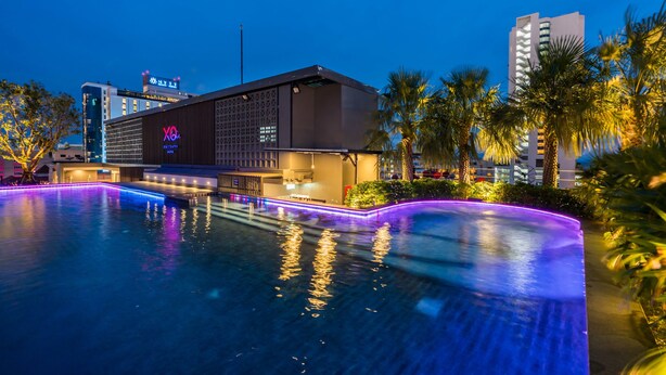 A hotel with a swimming pool, palm trees, and modern architecture. - XQ Pattaya Hotel (Pattaya)